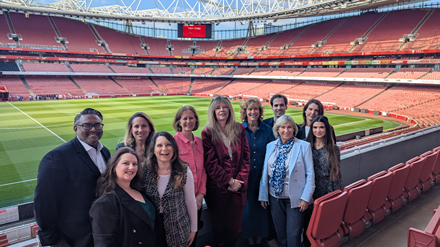 The London Convention Bureau team standing in front of the Emirates Stadium pitch