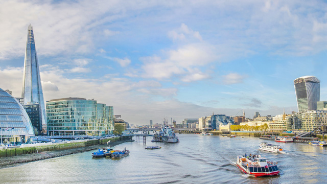 A calm river Thames with a few boats and the Shard in the background
