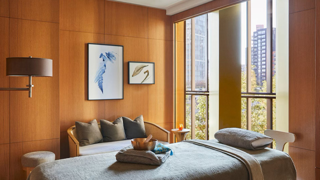 An interior of an elegant, contemporary hotel room with wood panelled walls and views of London.