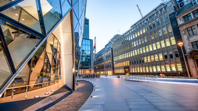 A clean, financial district street with modern and historic buildings on both sides.