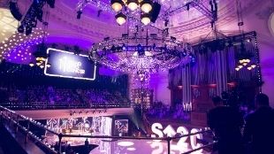 A large stage with purple lighting and a big chandelier at Central Hall Westminster in London.