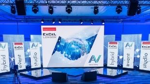 Big screen and banners surrounded by dark blue light at the event studio at ExCeL London.