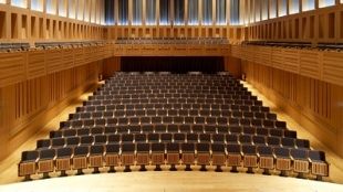 Neat rows with empty seats in the King's Place Events venue, all lit up in a warm light.