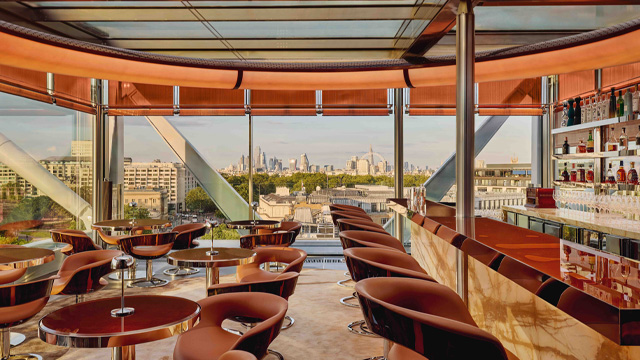 A London rooftop bar with a brightly lit, contemporary interior and panoramic city views.