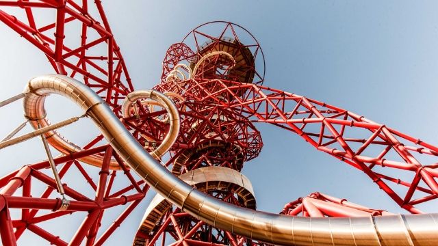 Looking up to the top of ArcelorMittal Orbit, a long tunnel slide within a red metal construct.