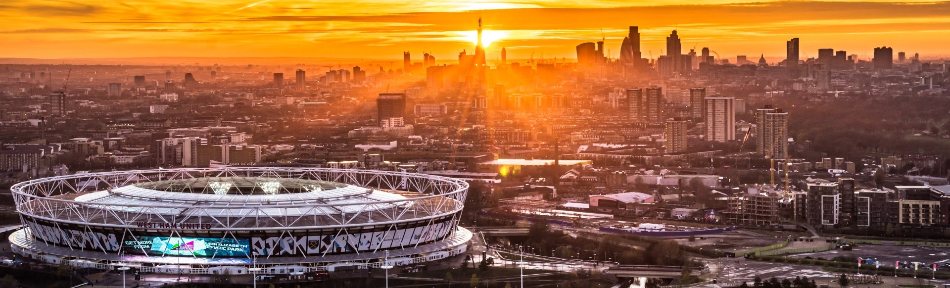 London skyline at sunset with London stadium in the foreground.