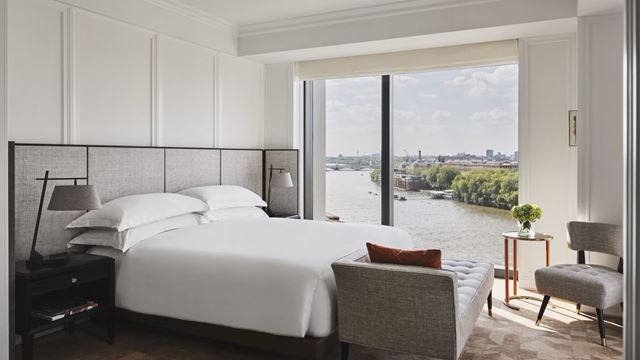 Room with a view at Park Hyatt London River Thames. Credit: Park Hyatt London River Thames. Image courtesy of Park Hyatt London River Thames. Hotel room with white beddings and huge window overlooking the river Thames and Battersea Park in London on a bright sunny day.