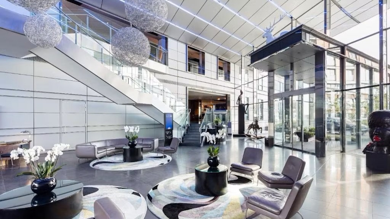 Sleek Radisson Blu Hotel lobby in Canary Wharf, east London, complete with glass doors and windows, grey seats and black tables with white flowers.
