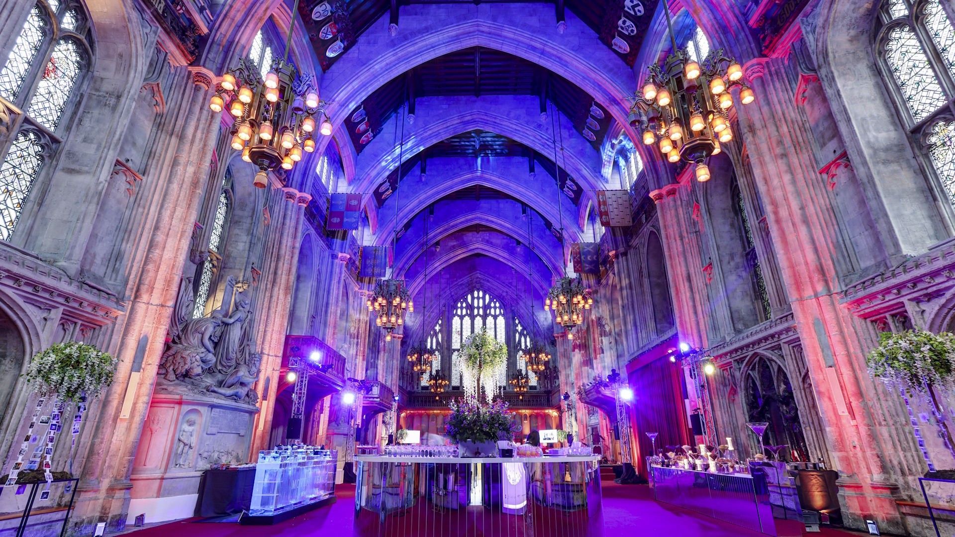 Guildhall's magnificent interior with grand columns, stained glass windows and arches on the ceiling, lit up in pink, yellow and blue lights.