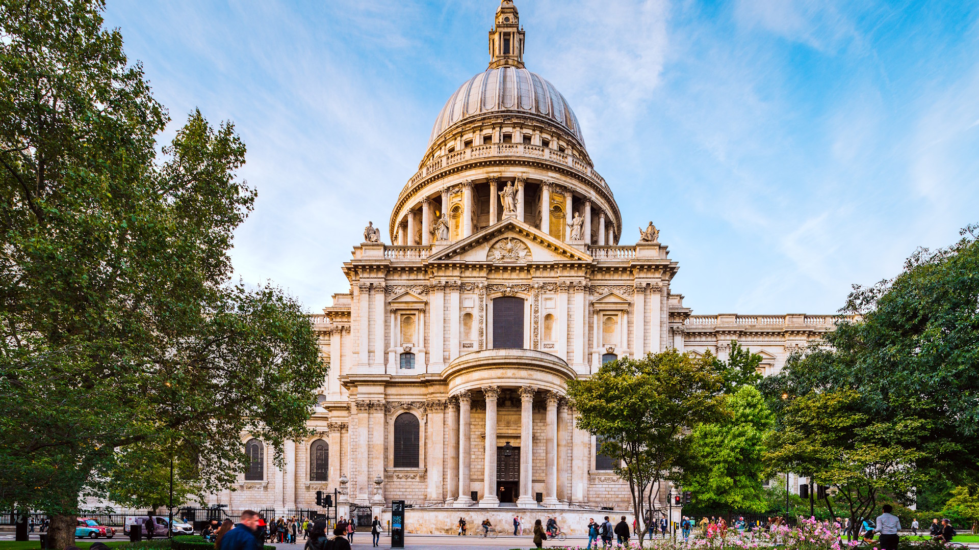 St Paul's Cathedral on a clear sunny day with blue sky and people walking past and up to the entrance.