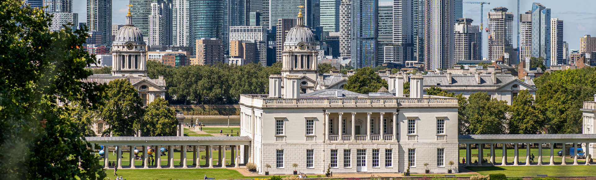 A view of the historic Queen's House in Greenwich with Canary Wharf skyscrapers in the background.