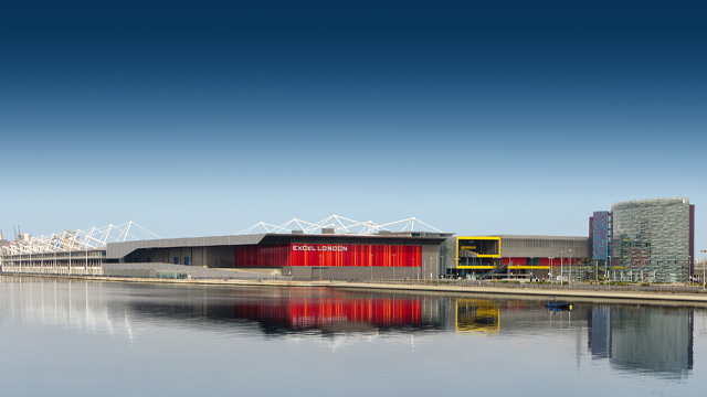 A panoramic view of a modern convention centre with the river Thames in the foreground.
