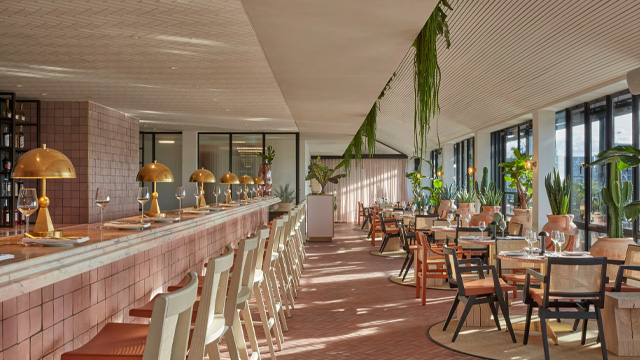 Interior of a contemporary, elegant bar with floor to ceiling windows with city views.