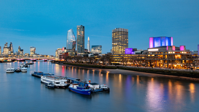 An evening view of the river Thames with illuminated buildings on the South Bank.