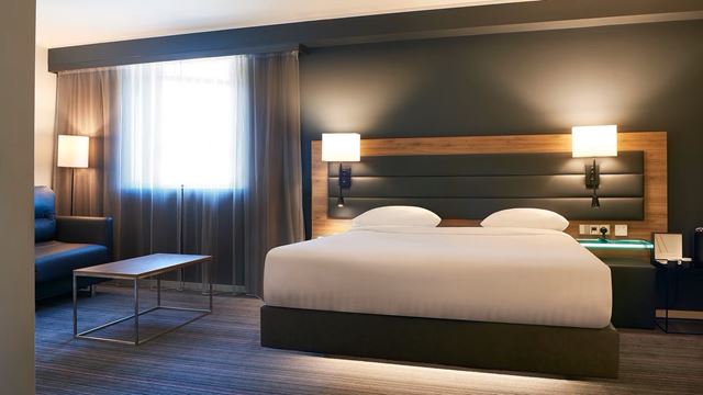 Enjoy a stay at Moxy London Stratford. Credit: Moxy London Stratford. Image courtesy of Moxy London Stratford. Double bed with white sheets, intimate lighting and dark walls at Moxy London Stratford.