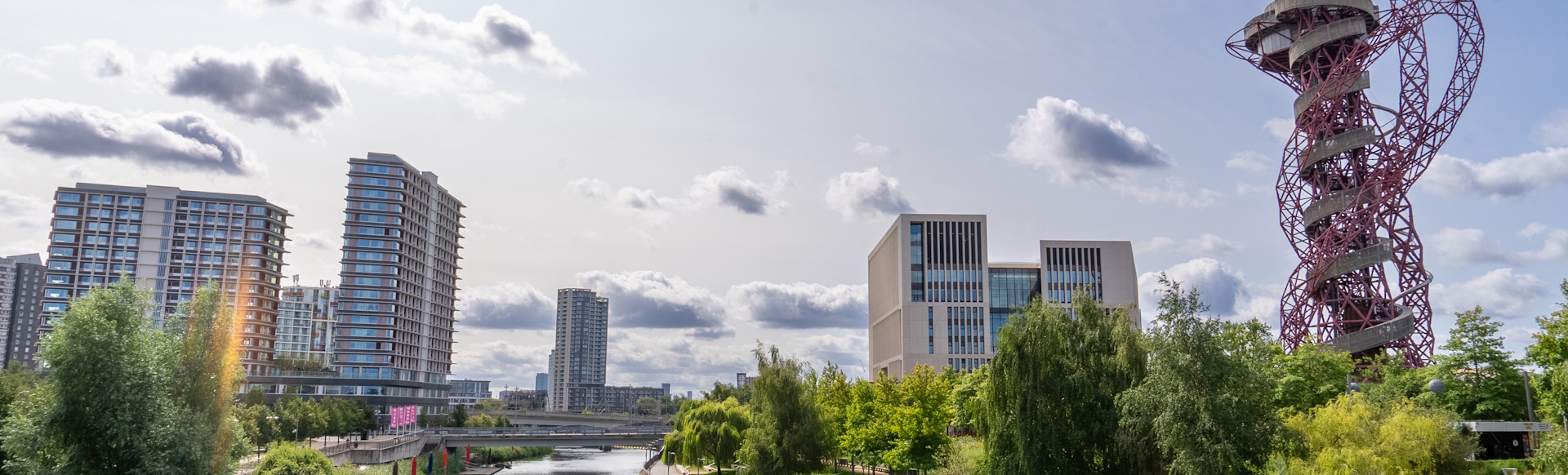 Stratford in east London with buildings, trees, the river and the iconic red sculpture known as ArcelorMittal Orbit.