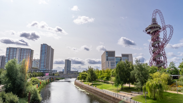 Stratford in east London with buildings, trees, the river and the iconic red sculpture known as ArcelorMittal Orbit.