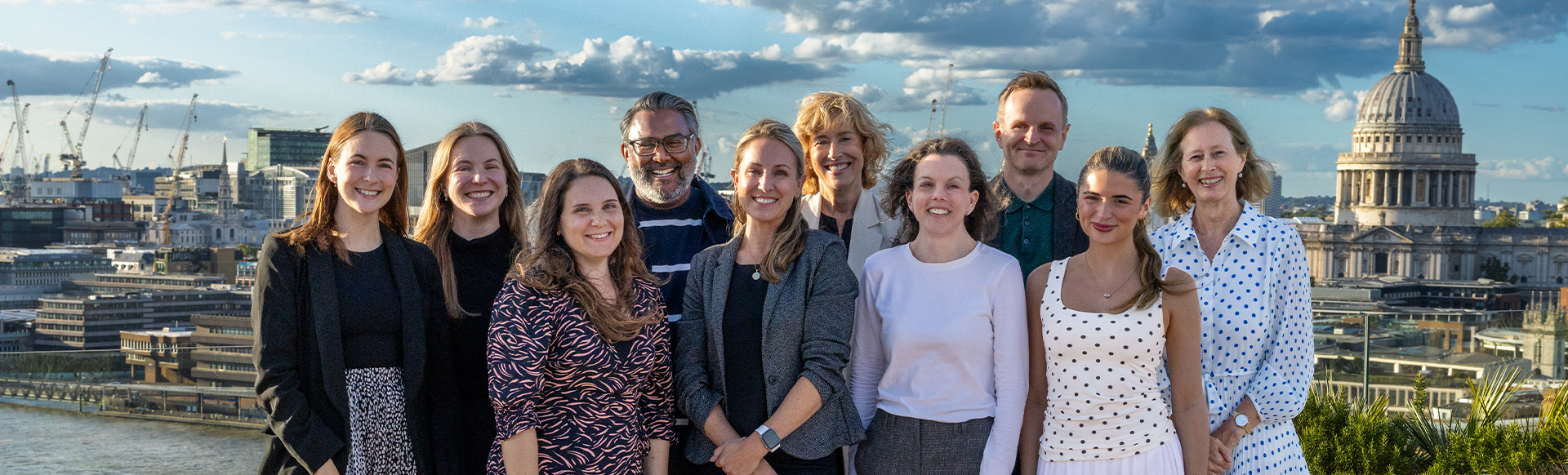A group picture of people in business attire smiling at the camera with London's St Paul's Cathedral visible in the background.