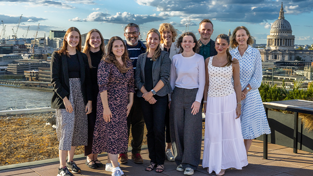 A group picture of people in business attire smiling at the camera with London's St Paul's Cathedral visible in the background.