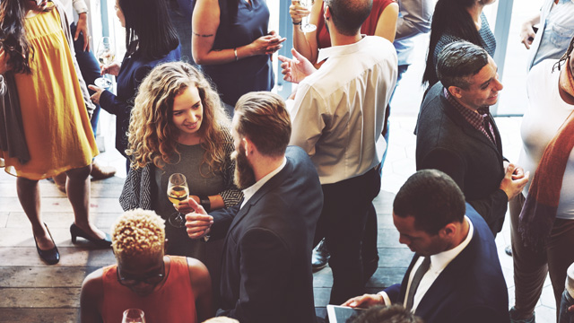 An aerial view of an event space full of people in business attire networking and talking.
