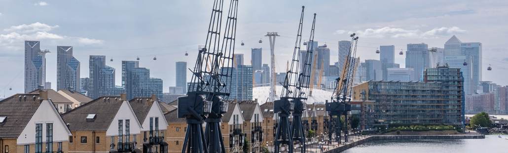 A skyline view of Canary Whary skyscrapers in the background with riverside homes and cranes in the foreground.