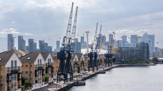 A skyline view of Canary Whary skyscrapers in the background with riverside homes and cranes in the foreground.