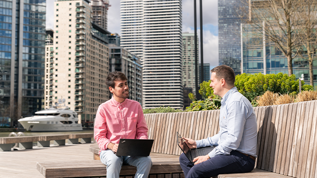 Two men with laptops having a meeting in Canary Wharf