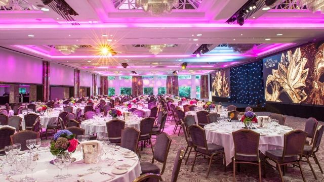Royal Lancaster London ballroom, decked round tables with a pink light ceiling.