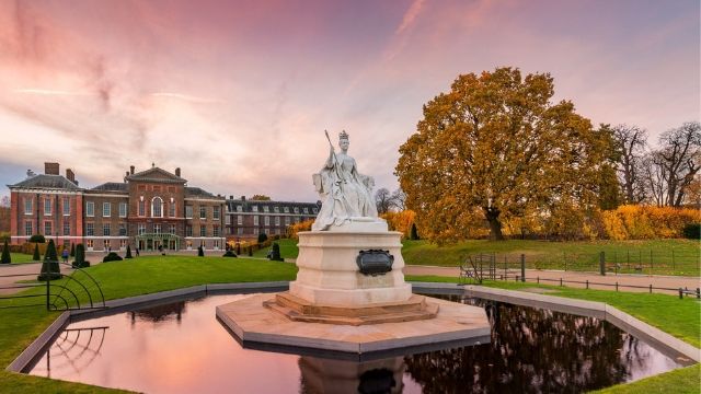 Fountain with a white statue in the gardens at Kensington Palace in London at sunset.