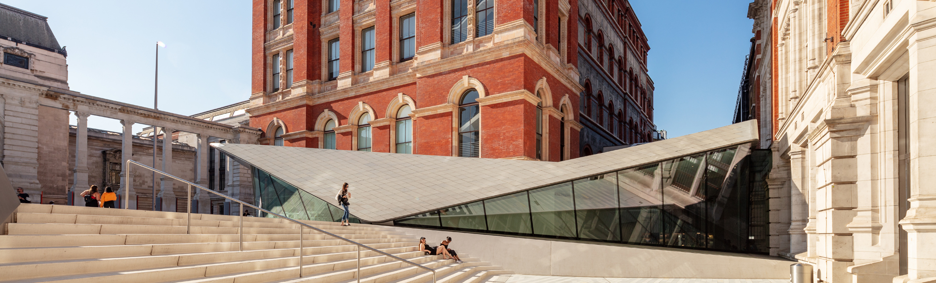 People sitting on stone staircase with old architecture buildings in the background.