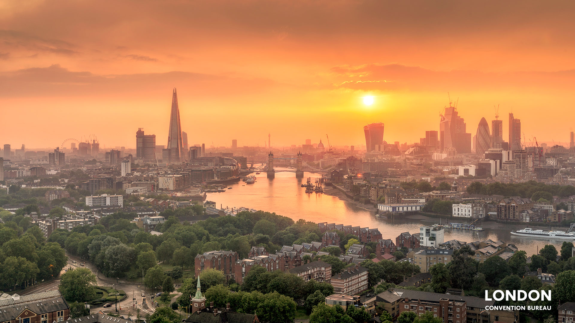 The London skyline and river Thames covered in orange light during sunset.