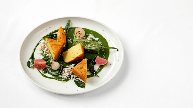 high angle shot of a small white plate with green sauce drizzled and chickpea gnocchi