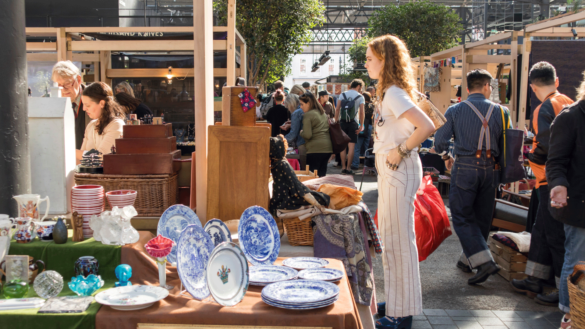 Girl looks at vintage items at a stall during Spitalfields Antique Market